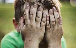child covering face in hands