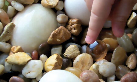 Child's fingers picking up a marble.