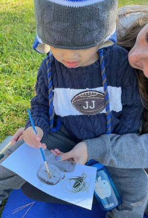 Child and teacher painting outdoors.