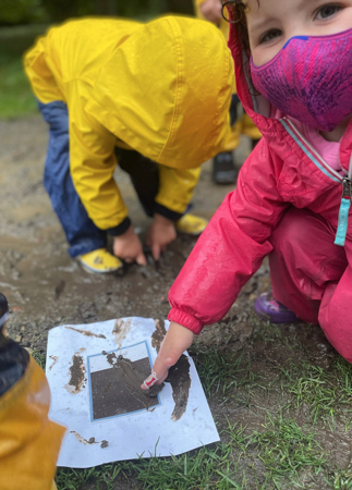Children painting with mud outdoors.