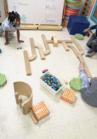Girl with blocks arranged on floor.