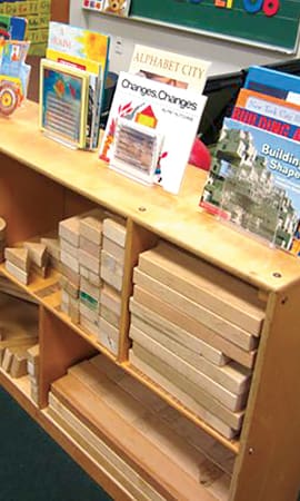 Blocks stacked away in a shelf with books on top.