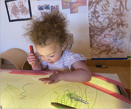 Child scribbling on a light table.