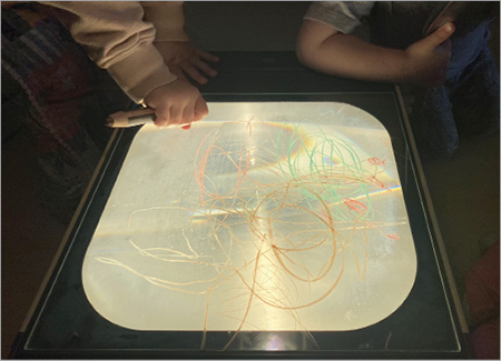 Child's hand scribbling on an overhead projector.