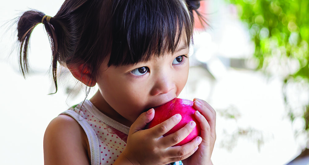 Young girl taking a bite out of an apple