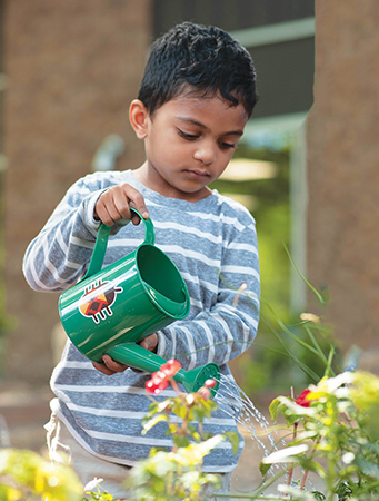 Young boy watering plants with watering can