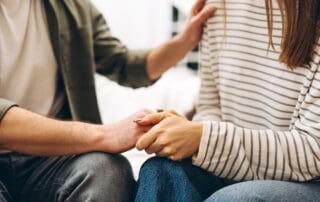 Person placing hand on other person's arm in comfort