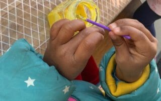 Child hands dipping brush into yellow paint
