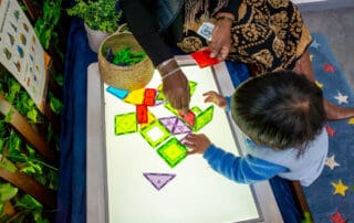 Educator and child building with blocks on a light table