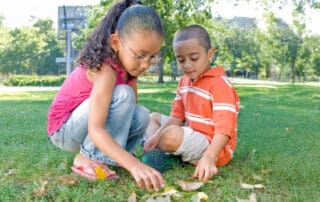 Two children exploring leaves outside