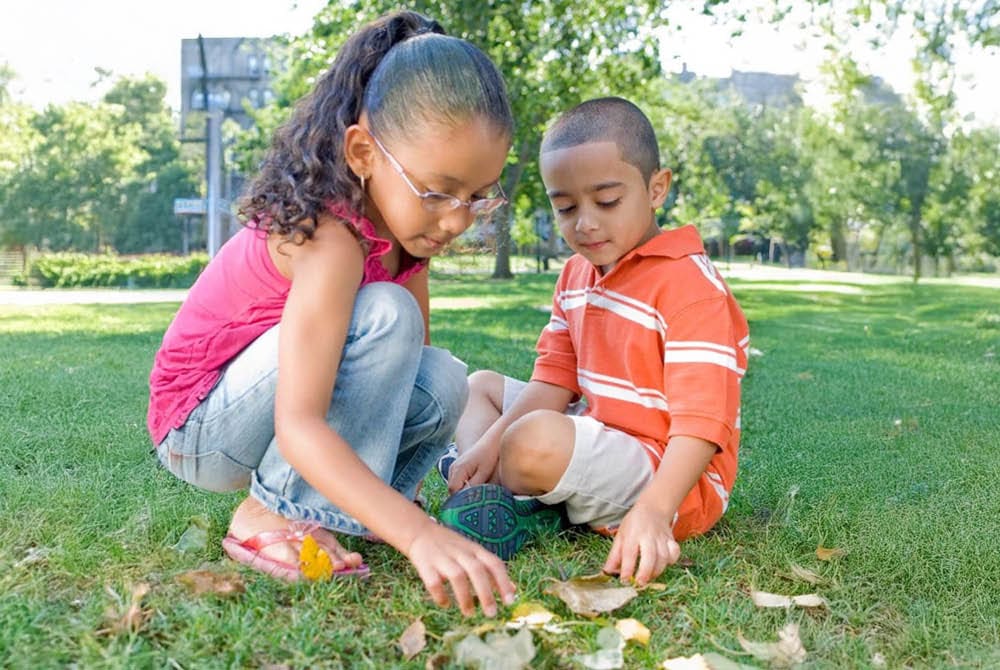 Two children exploring leaves outside