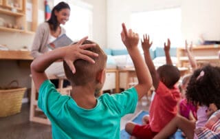 Children raising their hands in a classroom