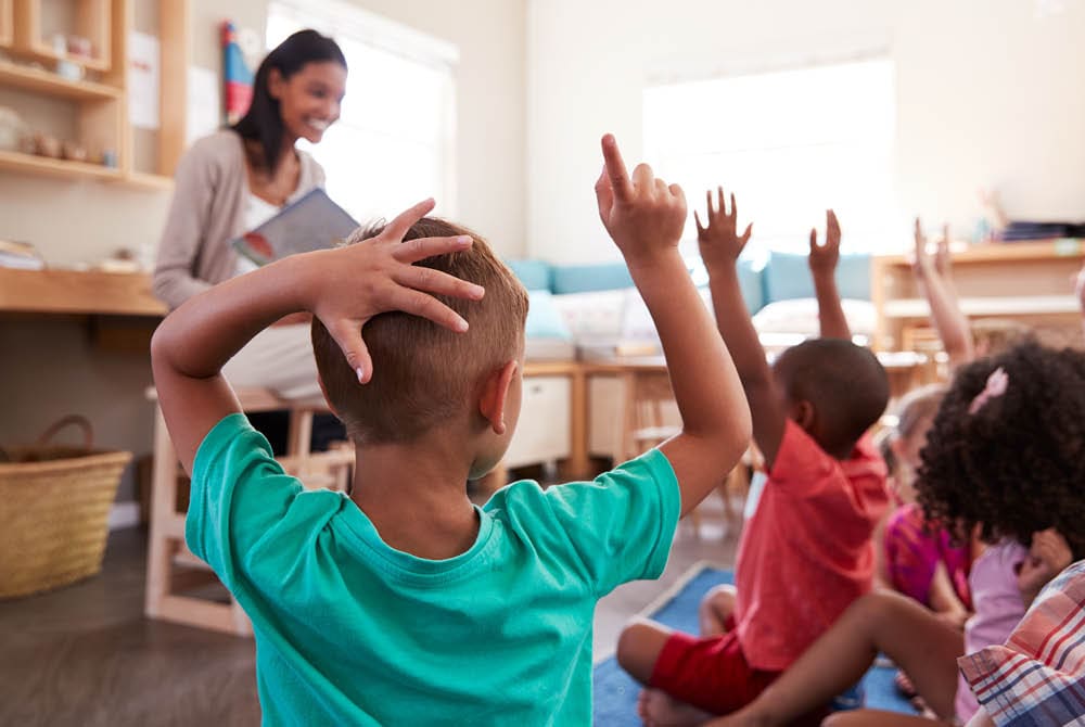 Children raising their hands in a classroom